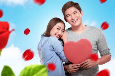 Kırmızı kalbi tutan Asyalı çiftler. Sevgililer Günü