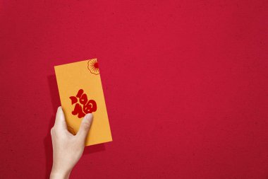 Elinde renkli arkaplanı olan altın zarflar (Angpao) tutuyordu. Mutlu Çin Yeni Yılı