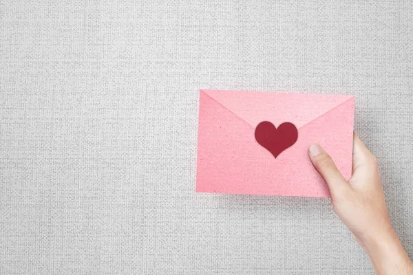 Human Hand Holding Pink Envelope Heart Textured Background — Stock Photo, Image