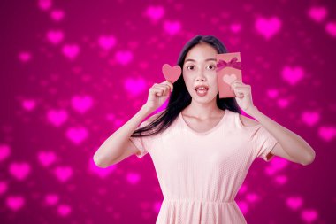 Elinde hediye kutusu olan Asyalı bir kadın ve renkli bir kalbi olan kırmızı bir kalp. Sevgililer Günü