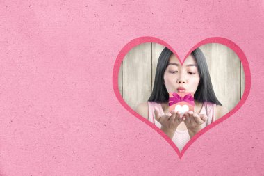 Asyalı kadın kırmızı kurdeleli pembe hediye kutusu ve kalbi tahta arka planda olan bir kalp gösteriyor. Sevgililer Günü