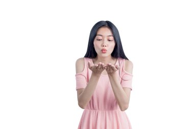 Asyalı bir kadın ellerine bir şey üflüyor beyaz arka planda izole edilmiş.