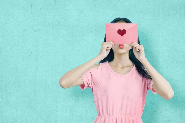 青い壁を背景にピンクのハートの封筒を持つアジアの女性 バレンタインデー — ストック写真