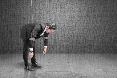 Asyalı işadamı, siyah duvarlı bir halatla kontrol ediliyor.