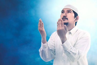 Asyalı Müslüman adam elini kaldırdı ve renkli bir geçmişle dua etti.