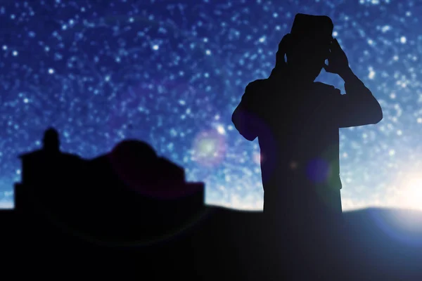 Silhouette of Muslim man in praying position (salat) with the night scene background