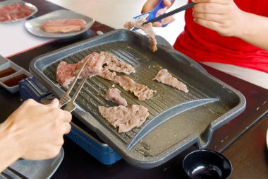 İnsanlar lokantada Kore barbeküsü yapıyor.