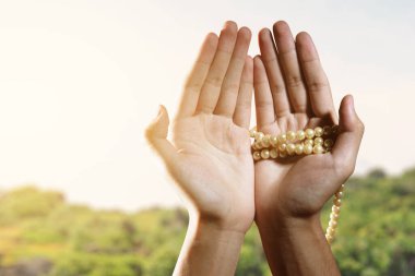 Müslüman bir adam elinde dua boncuklarıyla ve güneş ışığıyla dua ediyor.