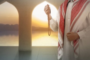 Müslüman bir adam camide dua boncuklarıyla dua ediyor.