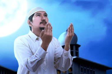 Asyalı Müslüman adam el kaldırdı ve gece sahne geçmişi ile dua etti.