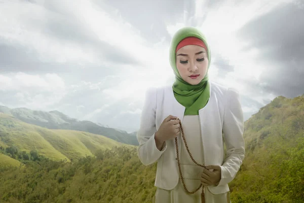 アジア系ムスリム女性のベールで祈りのビーズで彼女の手に劇的な空の背景と — ストック写真