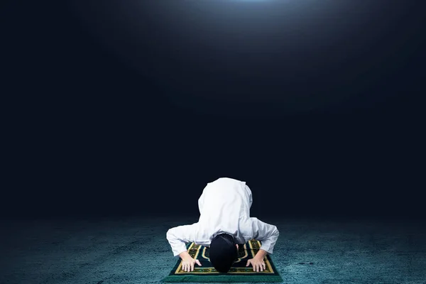 亚洲穆斯林男子在黑暗背景的祈祷地毯上祈祷 — 图库照片
