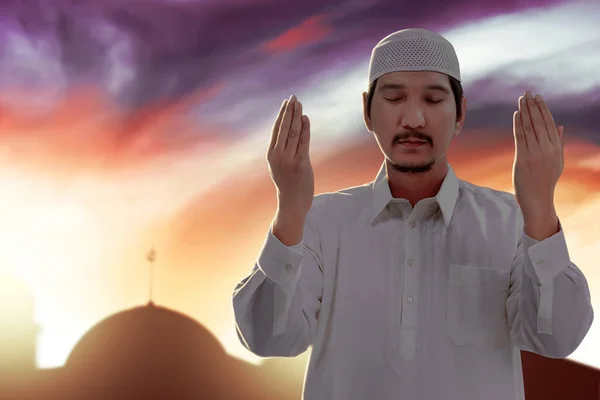 亚洲穆斯林男子举手表决站在那里 带着戏剧性的天空背景祈祷 — 图库照片