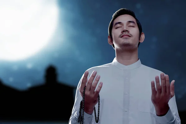 亚洲穆斯林男子双手拿着祈祷珠子在夜景的背景下祈祷 — 图库照片