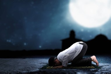 Geceleyin namaz kılan Asyalı Müslüman bir adam (namaz kılıyor) namaz kılıyor.