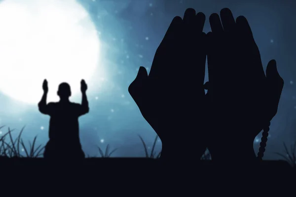 夜の風景を背景に手に祈りのビーズで祈るイスラム教徒の男のシルエット — ストック写真