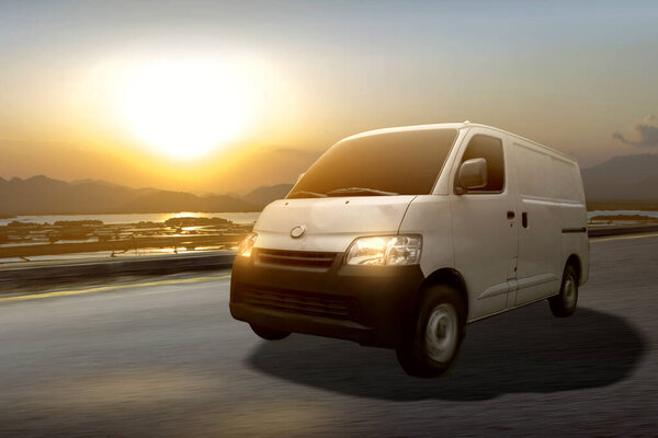 The white delivery van on the road with sunset sky background