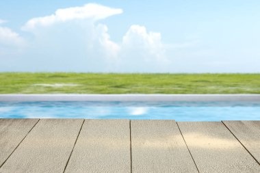 Göletli ahşap yol ve mavi gökyüzü arka planlı yeşil çimen.