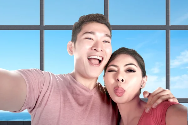亚洲夫妇带着滑稽的面容在海景度假胜地自拍 — 图库照片