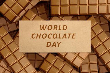 Kahverengi arka planda Dünya Çikolata Günü yazılı çikolata. Dünya Çikolata Günü