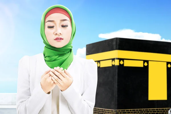 披着面纱站在那里祈祷的亚裔穆斯林妇女 带着Kaaba的景色和蓝天背景 — 图库照片