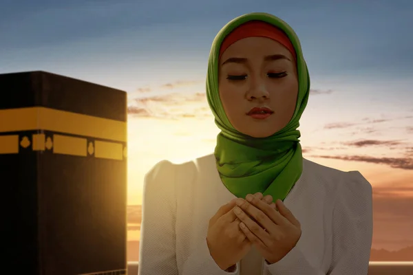 ベール立っているとカアバビューと日没のシーンの背景で祈るアジアのイスラム教徒の女性 — ストック写真