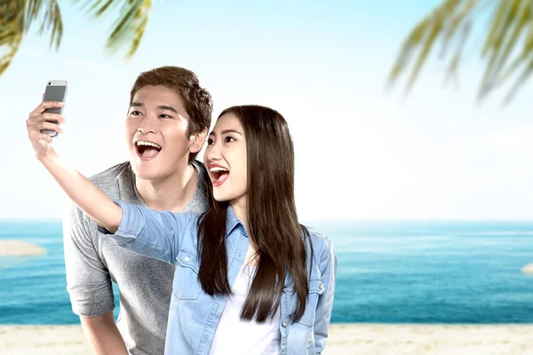 在蓝天背景的海滩上 一对亚洲夫妇带着滑稽的脸自拍 — 图库照片