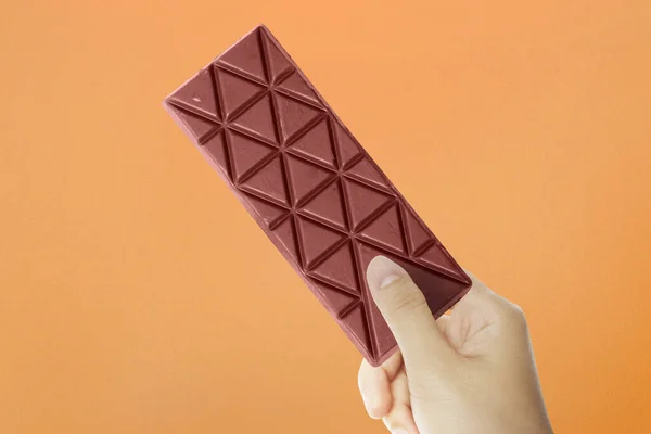 Mano Humana Sosteniendo Barra Chocolate Con Fondo Color —  Fotos de Stock