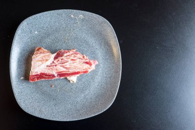 Siyah bir masada ızgara yapmak için çiğ et tabağı.