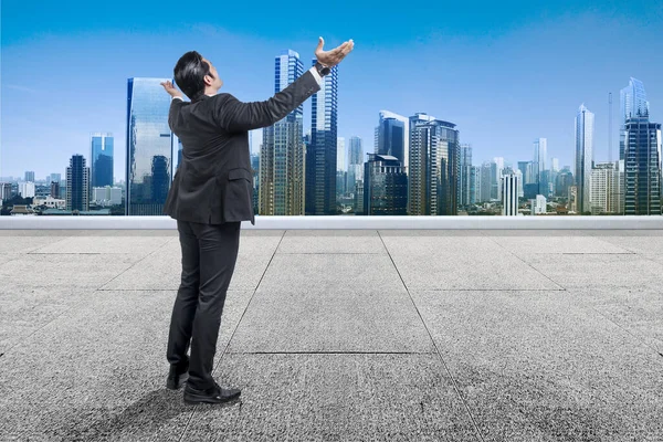 Tylny Widok Azjatyckiego Biznesmena Stojącego Podniesioną Ręką Dachu Wieżowcami Tle — Zdjęcie stockowe
