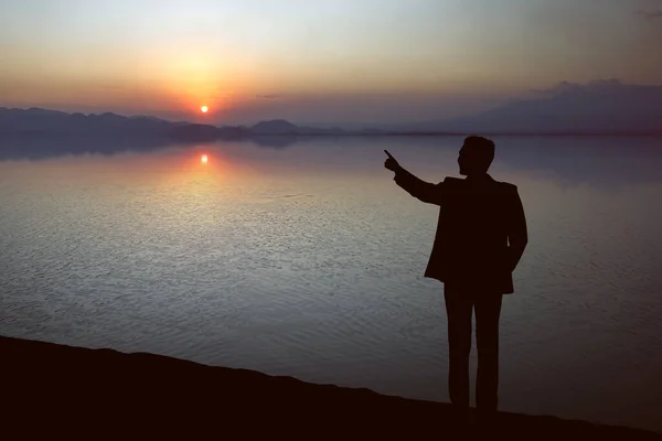 Siluet Pengusaha Menunjuk Sesuatu Danau Dengan Latar Langit Matahari Terbenam — Stok Foto