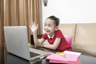 Bilgisayarlı Asyalı küçük kız evde online okul derslerine katılıyor. Karantina sırasında çevrimiçi eğitim