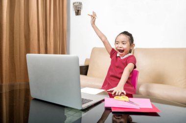 Bilgisayarlı Asyalı küçük kız evde online okul derslerine katılıyor. Karantina sırasında çevrimiçi eğitim
