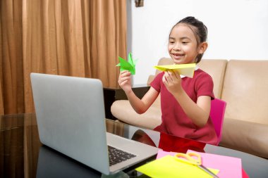 Bilgisayarlı Asyalı küçük kız evde online okul derslerine katılıyor. Karantina sırasında çevrimiçi eğitim