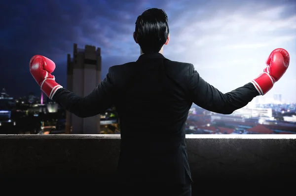 都市景観を背景とした赤いボクシンググローブを持つアジアのビジネスマンの背面図 — ストック写真