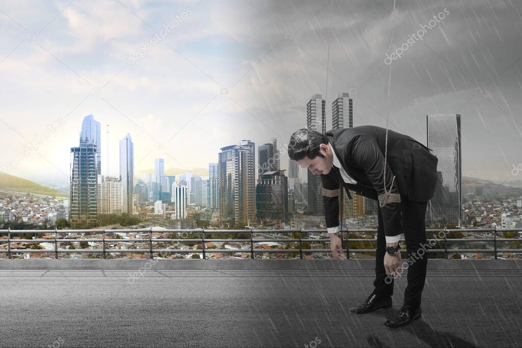 Asian businessman controlled with rope with different climates and cityscapes background