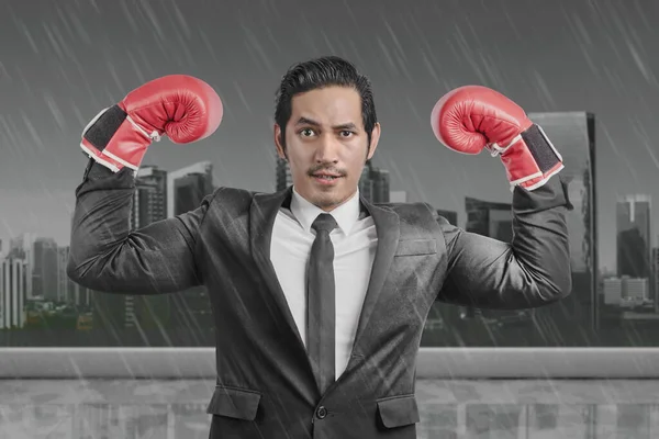 雨の背景を持つ赤いボクシングの手袋を持つアジアのビジネスマン — ストック写真