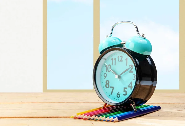 Schreibtisch Mit Uhr Und Reihe Von Buntstiften Mit Fensterglashintergrund Zurück — Stockfoto