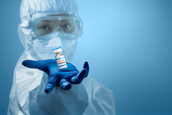 防護服と手袋を身に着けている健康労働者の女性青の背景を持つCovid 19ワクチン — ストック写真