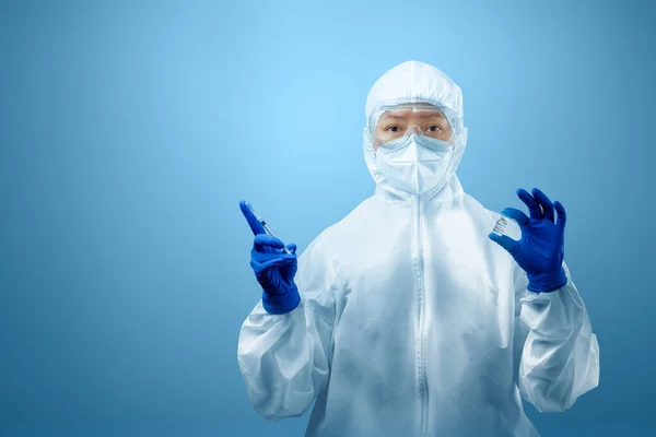 防護服と手袋を身に着けている健康労働者の女性青の背景を持つCovid 19ワクチン — ストック写真
