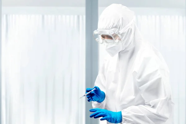 保護スーツと手袋を持っている健康労働者の女性病院でCovid 19ワクチンを保持 — ストック写真