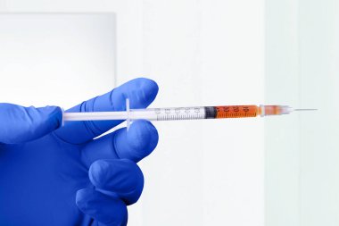 Sağlık işçisi elinde eldivenlerle elinde şırıngayla hastanede 19 adet aşı taşıyor.