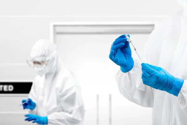 Health worker woman with a protective suit and gloves holding covid 19 vaccines on the hospital