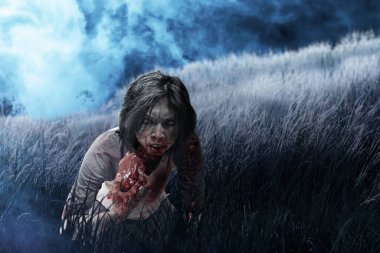 Vücudunda kan ve yara olan korkunç bir zombi tarladaki çiğ eti yiyor.