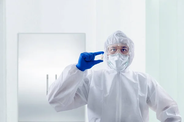 保護スーツと手袋を持つ健康労働者の男病院でCovid 19ワクチンを保持 — ストック写真