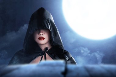 Gece manzaralı pelerinli Asyalı cadı kadın.