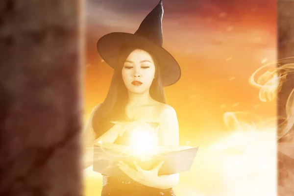 Азиатская Ведьма Книгой Заклинаний Показывающей Магию Руке Драматическим Фоном — стоковое фото