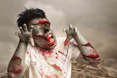 Vücudunda kan ve yara olan korkunç bir zombi sahada yürüyor.