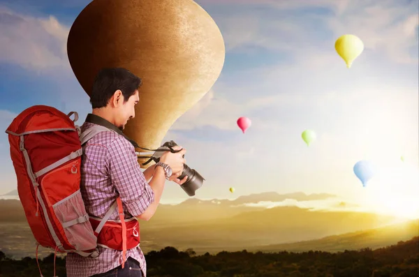 バックパックとカメラを持つアジアの男は カラフルな気球を見て日没の空の背景と飛んで — ストック写真