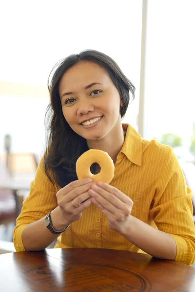 魅力的な女性はカフェでドーナツを食べる — ストック写真